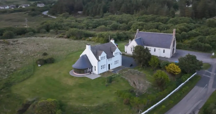 Aerial drone view of Scottish Cottage and its grounds surrounded by green Highland fields
